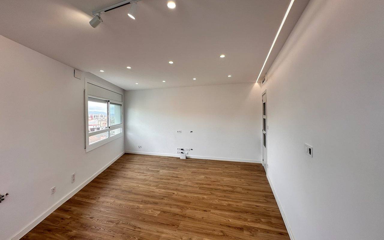 Habitación reformada por G-Instal con suelo laminado nuevo, paredes pintadas e iluminación empotrada
